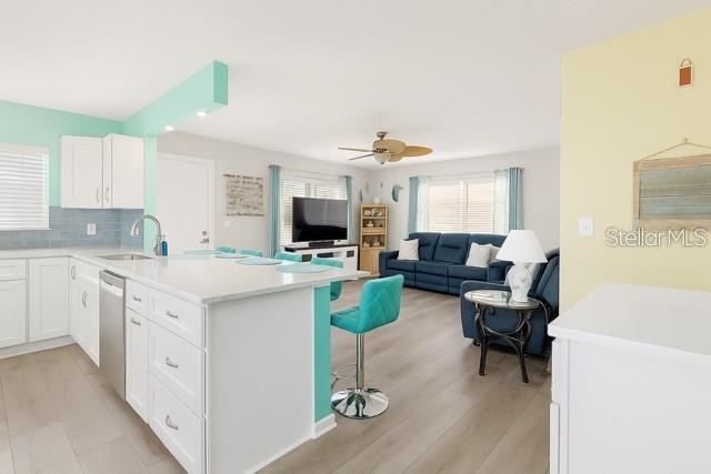 A bright, open-concept kitchen with white cabinetry and a teal island overlooks a living room — 4860 S ATLANTIC AVENUE UNIT 1010, NEW SMYRNA BEACH, FL
