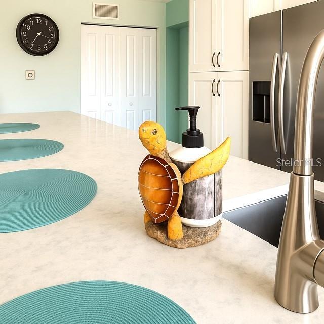A kitchen island features a turtle-shaped soap dispenser, teal placemats, and a stainless steel faucet — 4860 S ATLANTIC AVENUE UNIT 1010, NEW SMYRNA BEACH, FL