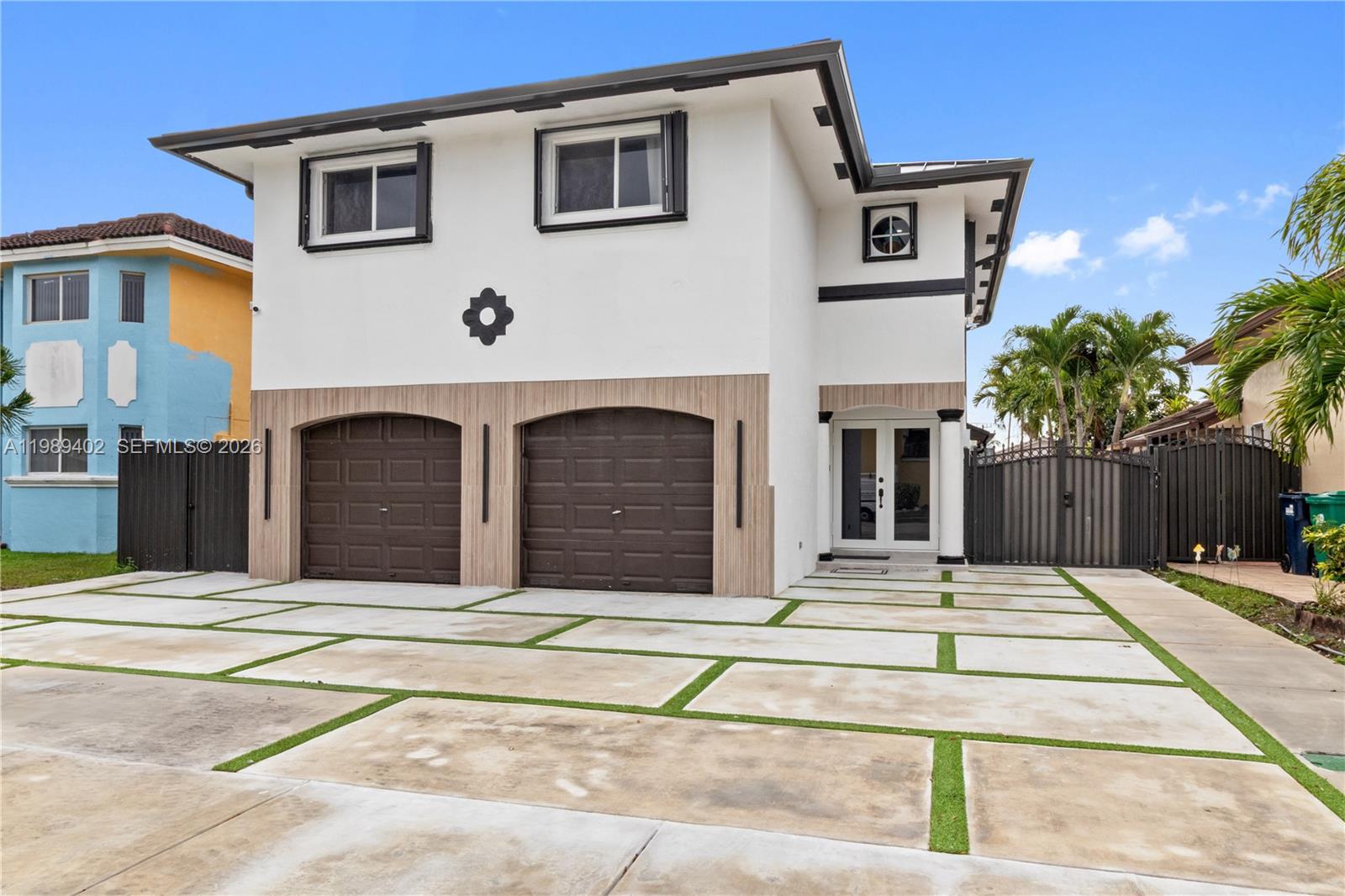 A two-story house features a white exterior, two brown garage doors, and a paved driveway — 14052 SW 167th Ter, Miami FL 33177, MIAMI, FL