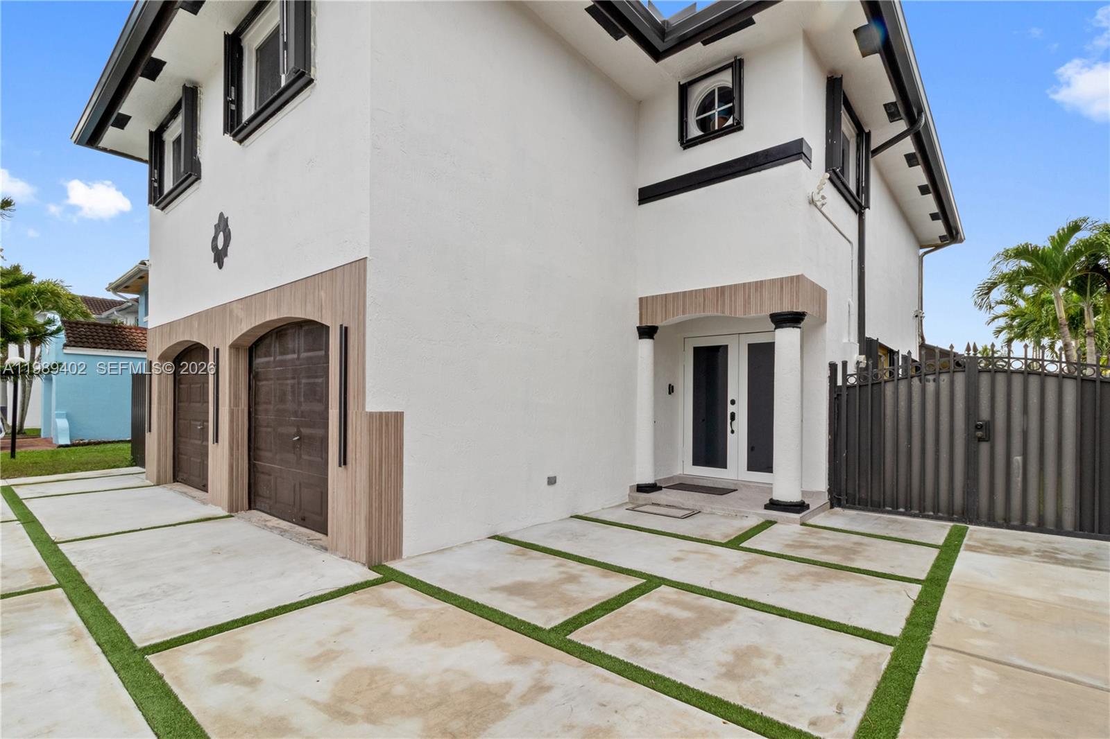 The exterior of a two-story house features a concrete driveway, garage doors, and double doors — 14052 SW 167th Ter, Miami FL 33177, MIAMI, FL
