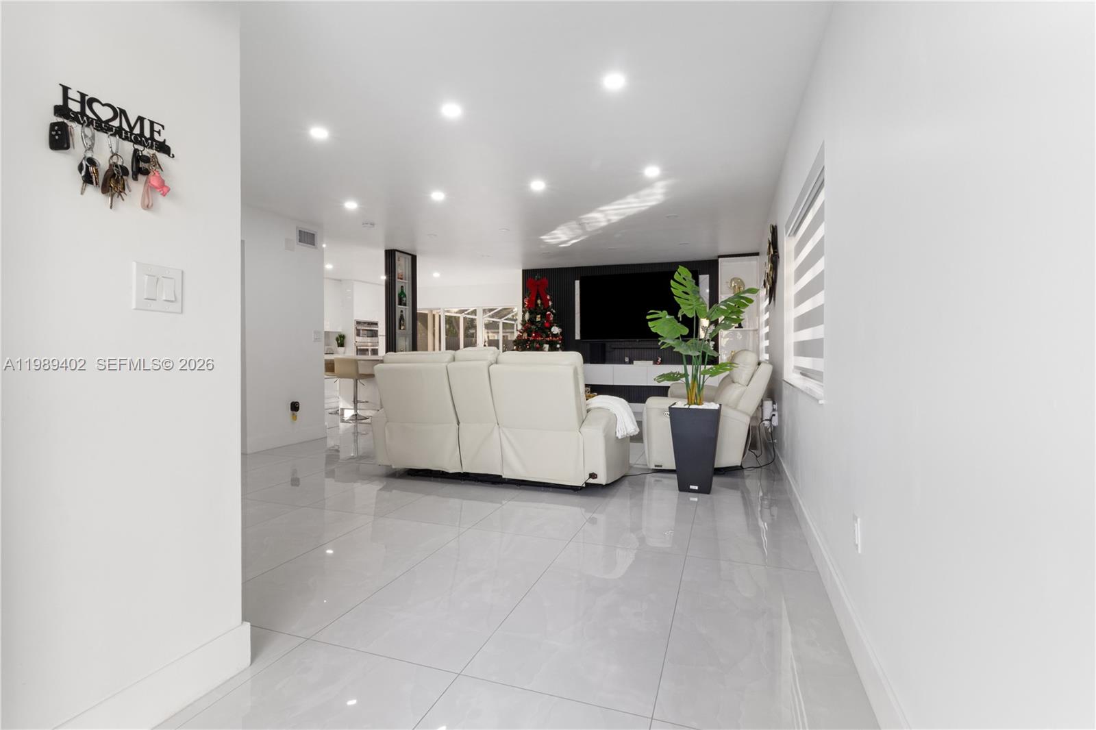A modern living room features white tile floors, a white sofa, and recessed ceiling lighting — 14052 SW 167th Ter, Miami FL 33177, MIAMI, FL