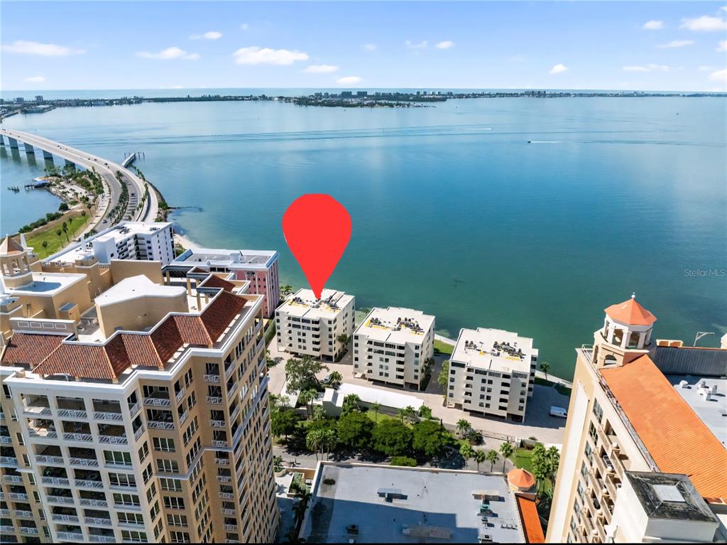 An aerial view shows waterfront condominium buildings along a bay near a bridge — 97 SUNSET DRIVE UNIT 501, SARASOTA, FL