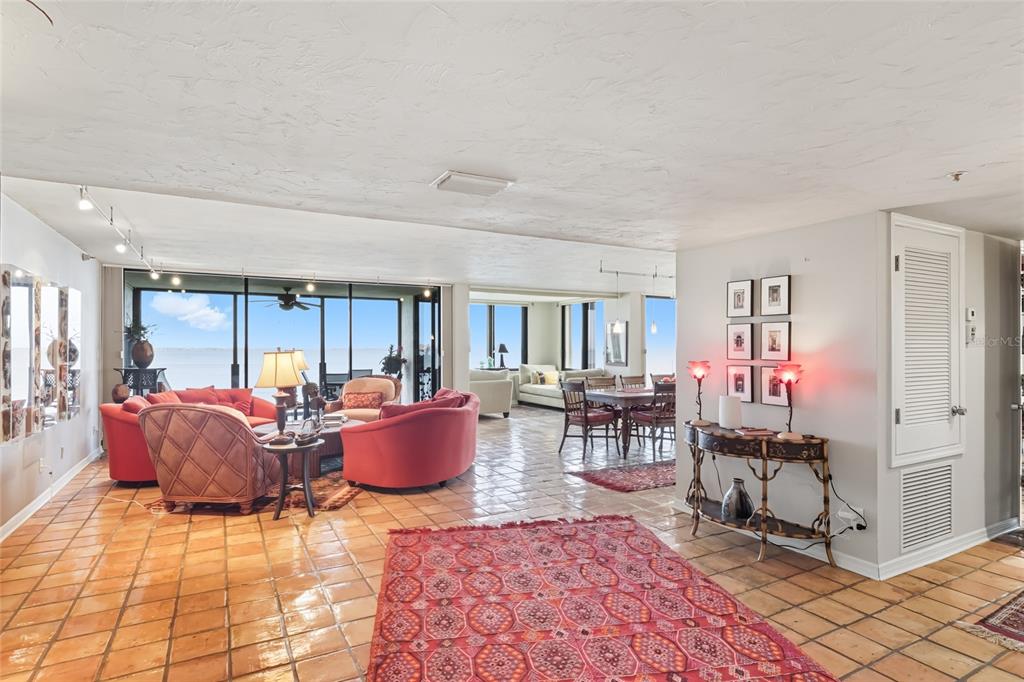 A spacious living and dining area features tile floors, red furniture, and large glass windows — 97 SUNSET DRIVE UNIT 501, SARASOTA, FL