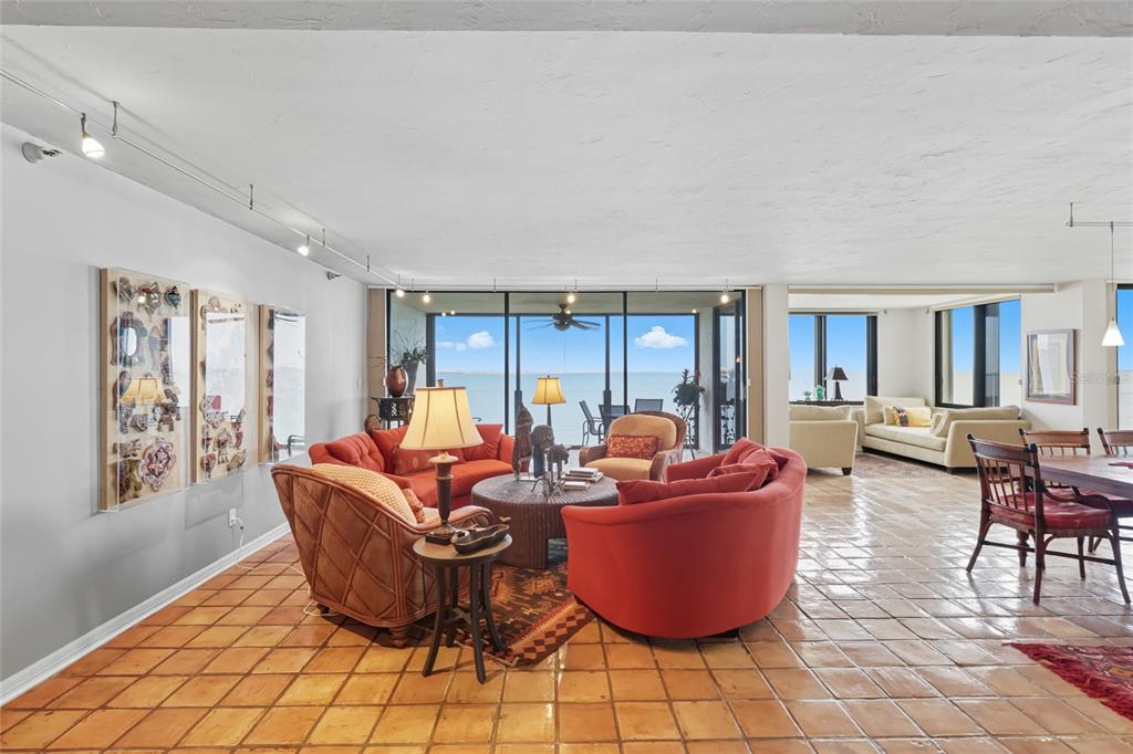 A spacious living and dining area features terracotta tile floors, track lighting, and floor-to-ceiling windows — 97 SUNSET DRIVE UNIT 501, SARASOTA, FL