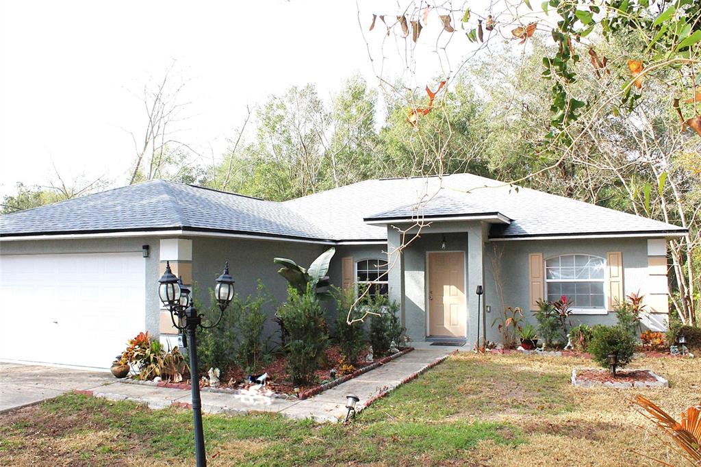 A single-story house with a gray stucco exterior, a two-car garage, and a front walkway — 42 DOGWOOD DRIVE COURSE, OCALA, FL