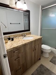 A bathroom features a wood vanity with a granite countertop, a mirror, and a shower — 1100 NE 191st St # 24E, Miami FL 33179, MIAMI, FL