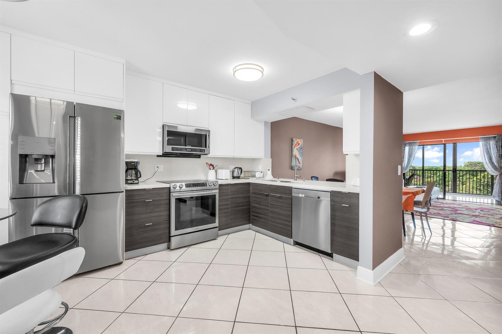 A modern kitchen features white upper cabinets, dark wood lower cabinets, and stainless steel appliances — 14475 Strathmore Lane # 602, Delray Beach FL 33446, DELRAY BEACH, FL