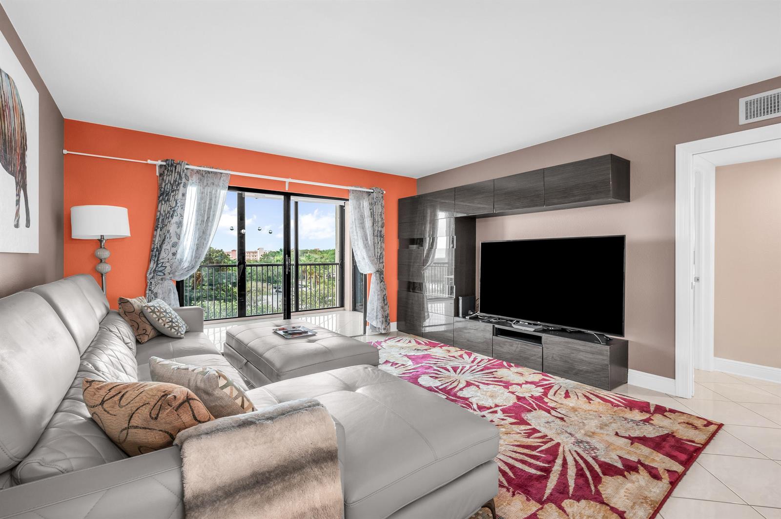 A dining room features a table with white chairs, orange walls, and dark cabinetry — 14475 Strathmore Lane # 602, Delray Beach FL 33446, DELRAY BEACH, FL