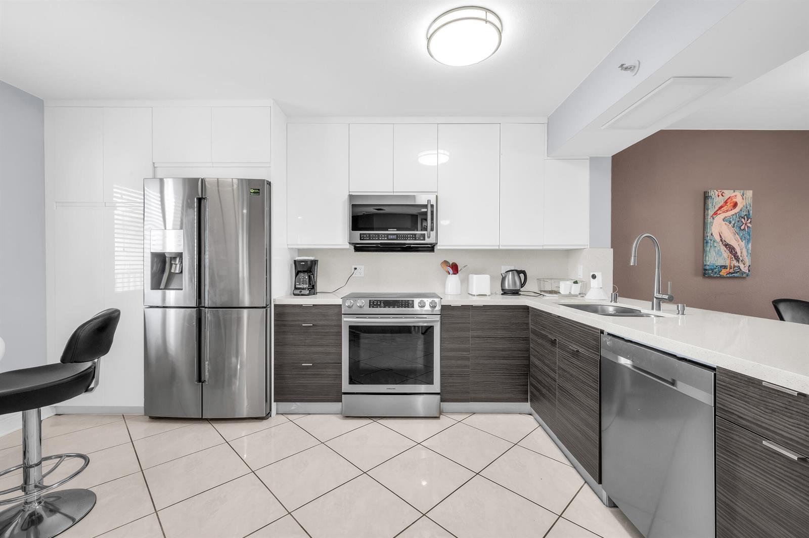 A dining area and living room with tile floors, a gray sofa, and orange walls — 14475 Strathmore Lane # 602, Delray Beach FL 33446, DELRAY BEACH, FL