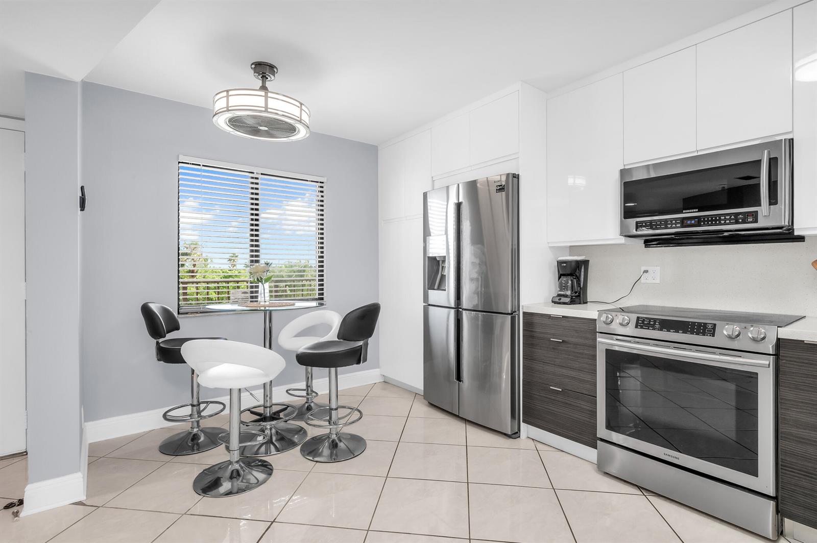 A living room features a gray sectional sofa, a large television unit, and a patterned rug — 14475 Strathmore Lane # 602, Delray Beach FL 33446, DELRAY BEACH, FL