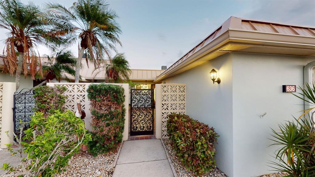 A walkway leads to a gated courtyard entrance of a house with a metal roof — 636 BOCA CIEGA POINT BOULEVARD S, ST PETERSBURG, FL