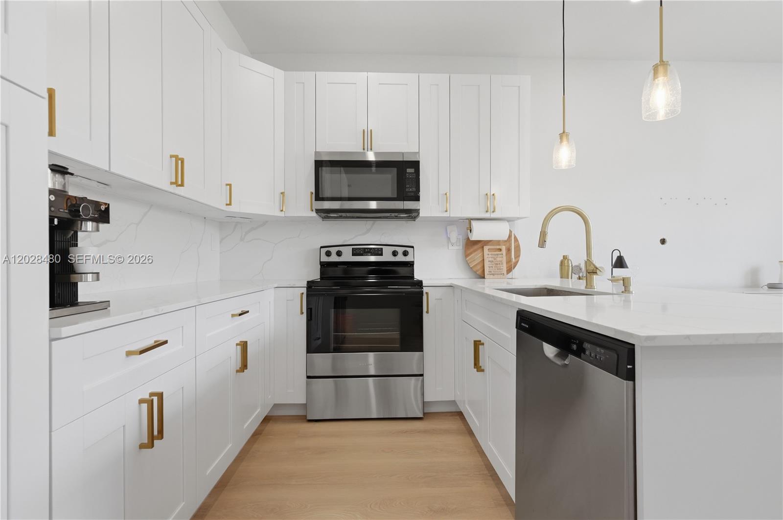 A modern kitchen features white cabinets, stainless steel appliances, gold hardware, and marble-look countertops — 4425 SW 160th Ave # 213, Miramar FL 33027, MIRAMAR, FL