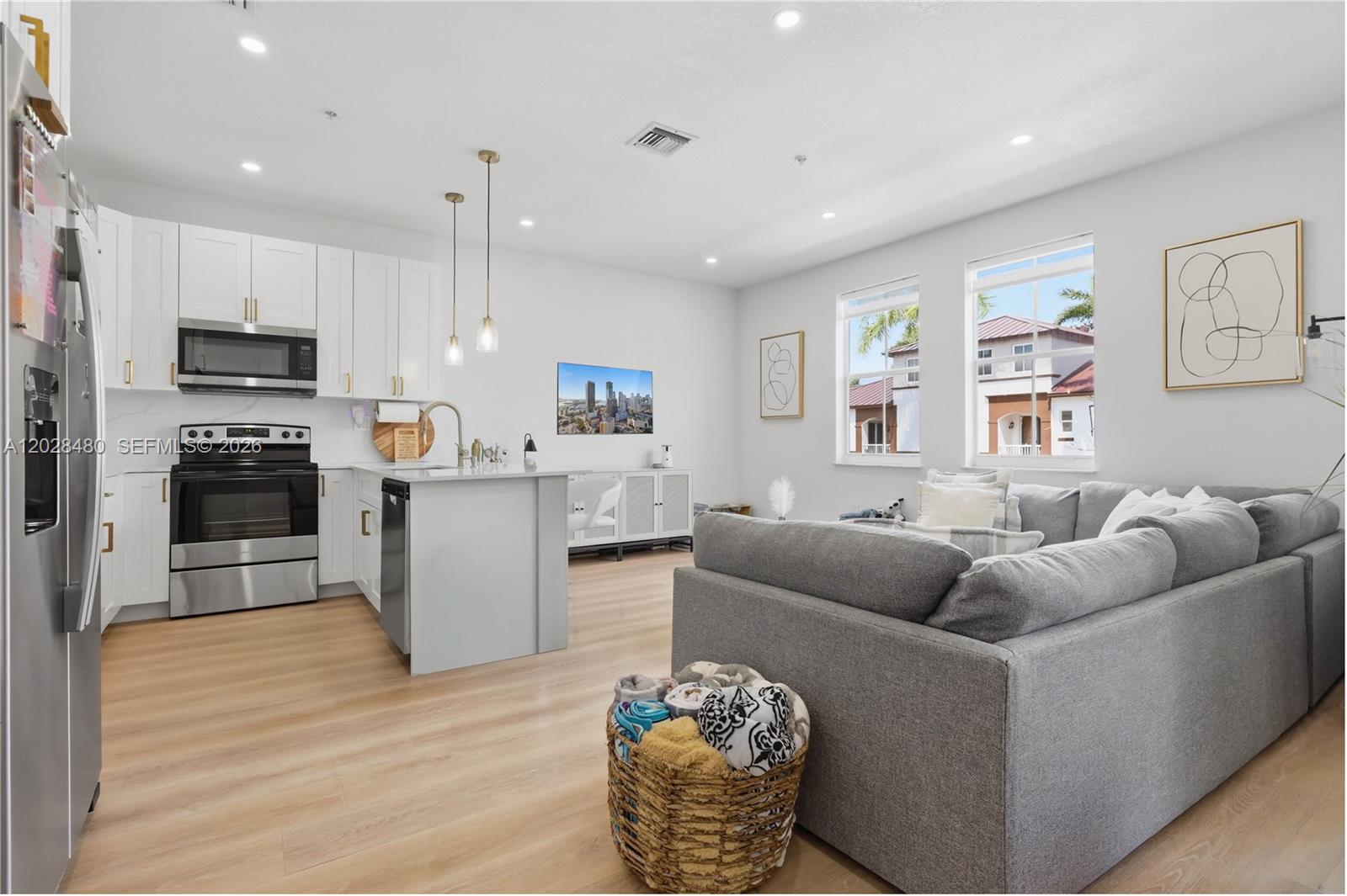 A modern open-concept kitchen and living area with white cabinets, stainless appliances, and gray furniture — 4425 SW 160th Ave # 213, Miramar FL 33027, MIRAMAR, FL