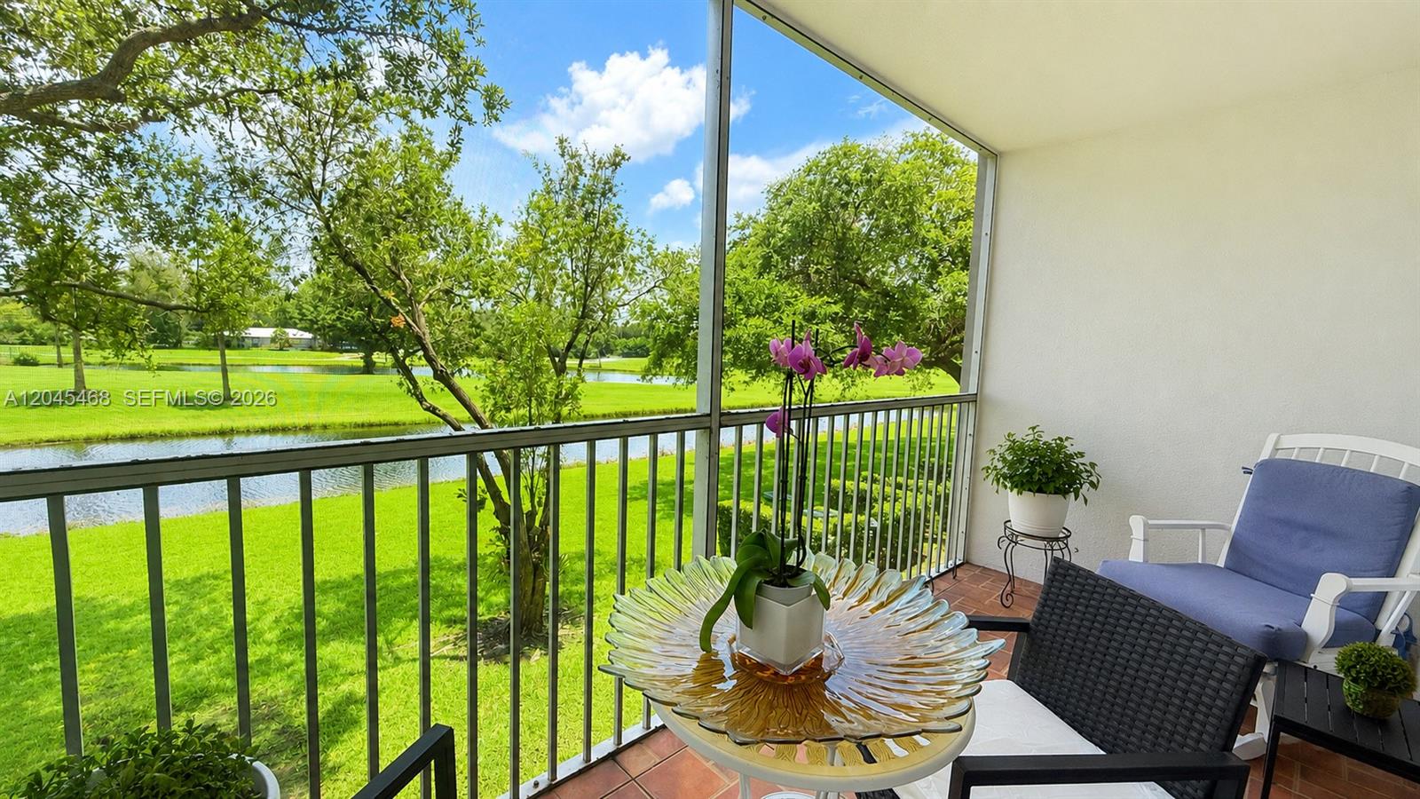 A screened-in balcony overlooks a grassy lawn, trees, and a small pond — 1151 SW 128th Ter # 206D, Pembroke Pines FL 33027, PEMBROKE PINES, FL