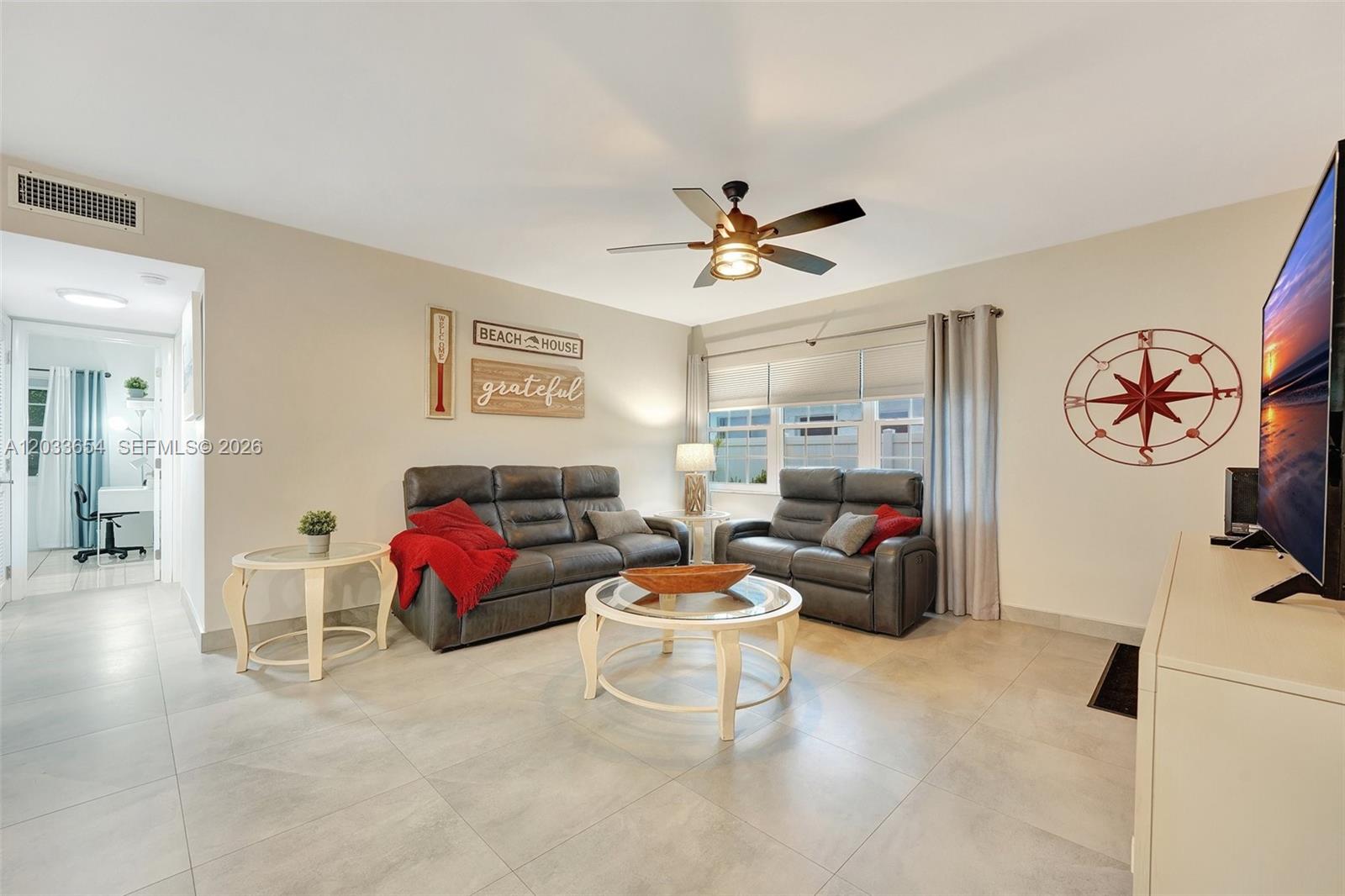 A living room features gray leather sofas, a round coffee table, and tile flooring — 221 SE 9th Ave # 102, Pompano Beach FL 33060, POMPANO BEACH, FL