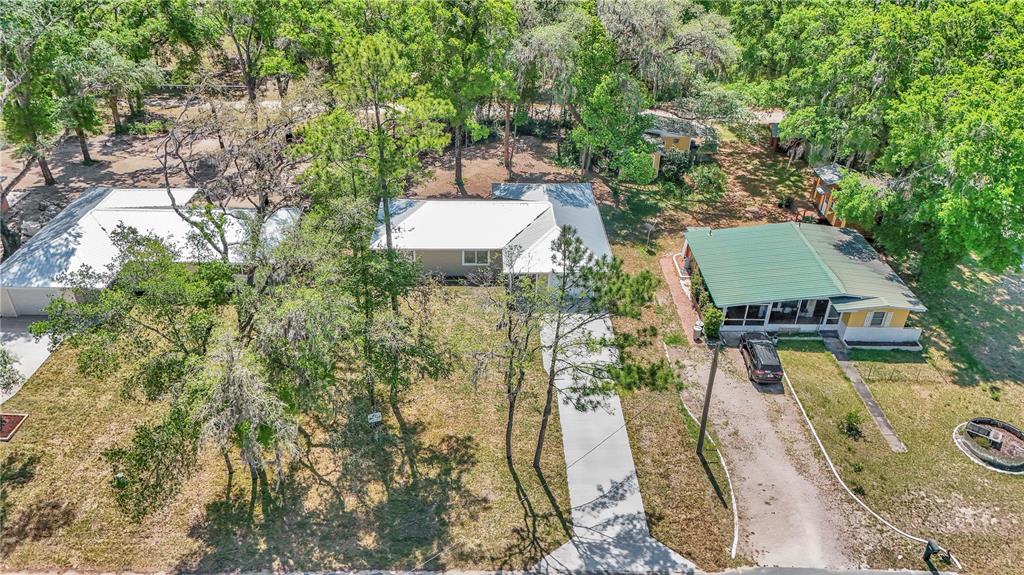 An aerial view shows two houses with metal roofs surrounded by trees and grassy yards — 2788 W CYPRESS DRIVE, DUNNELLON, FL