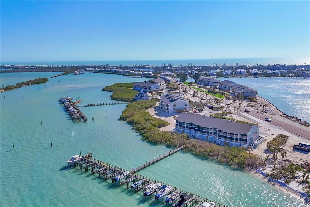 An aerial view shows a coastal resort with multiple buildings, a long dock, and boats — 6040 BOCA GRANDE CAUSEWAY UNIT A2, BOCA GRANDE, FL