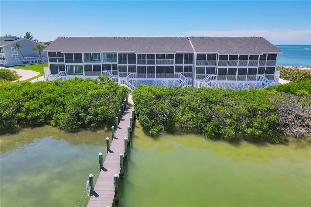 An aerial view shows a multi-story waterfront building with screened balconies and a wooden dock — 6040 BOCA GRANDE CAUSEWAY UNIT A2, BOCA GRANDE, FL