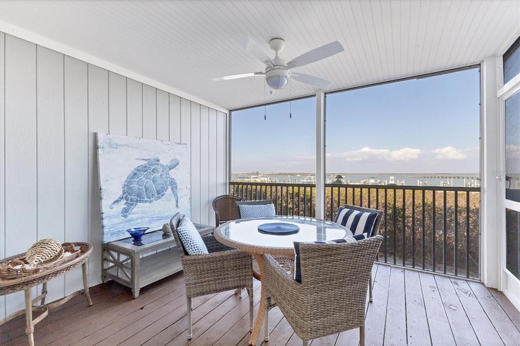A screened-in porch features a dining set, a turtle painting, and a water view — 6040 BOCA GRANDE CAUSEWAY UNIT A2, BOCA GRANDE, FL