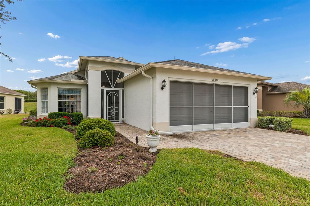 A single-story house with a white exterior, a paved driveway, and a screened garage door — 18452 FAIRWAY GREEN DRIVE, HUDSON, FL