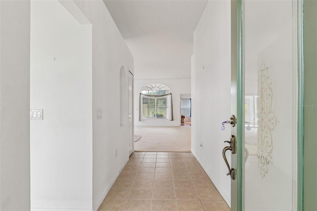 A tiled entryway leads into a carpeted living area with a large arched window — 18452 FAIRWAY GREEN DRIVE, HUDSON, FL