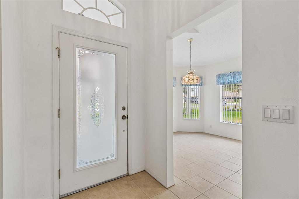 An entryway features a white front door with a decorative glass insert and tiled flooring — 18452 FAIRWAY GREEN DRIVE, HUDSON, FL