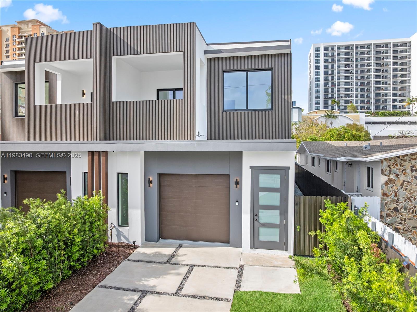 A modern two-story townhouse features a garage, a glass-paneled front door, and slatted wood siding — 3187 SW 23rd St, Miami FL 33145, MIAMI, FL
