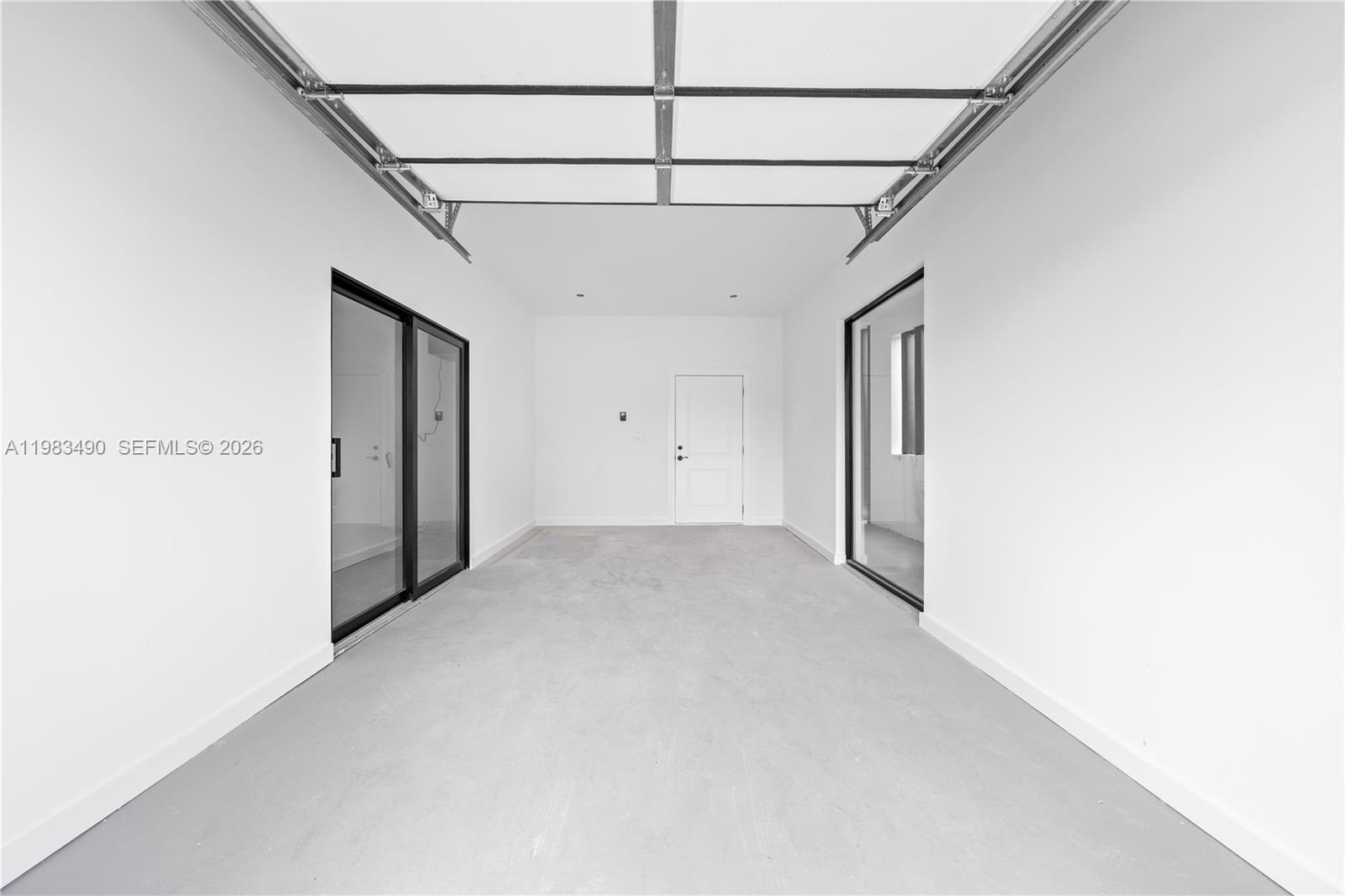 This is a minimalist, unfinished garage space with white walls, a concrete floor, and glass doors — 3187 SW 23rd St, Miami FL 33145, MIAMI, FL