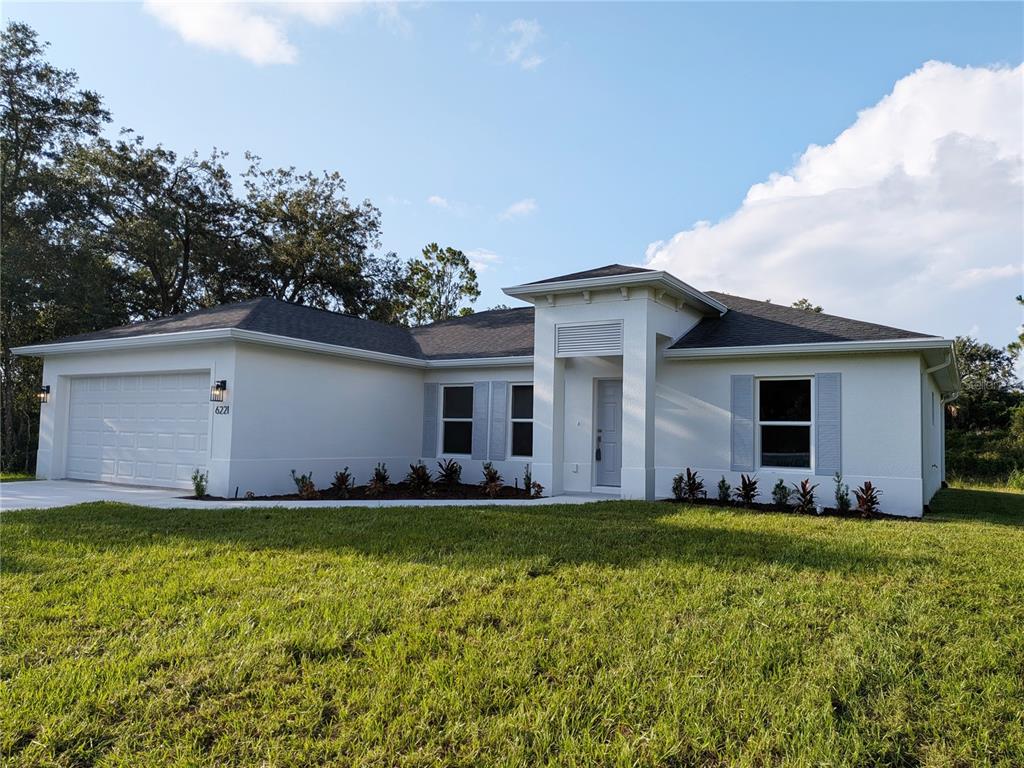 A single-story white stucco house features a two-car garage and a central recessed entryway — 6221 LACHINE AVENUE, NORTH PORT, FL
