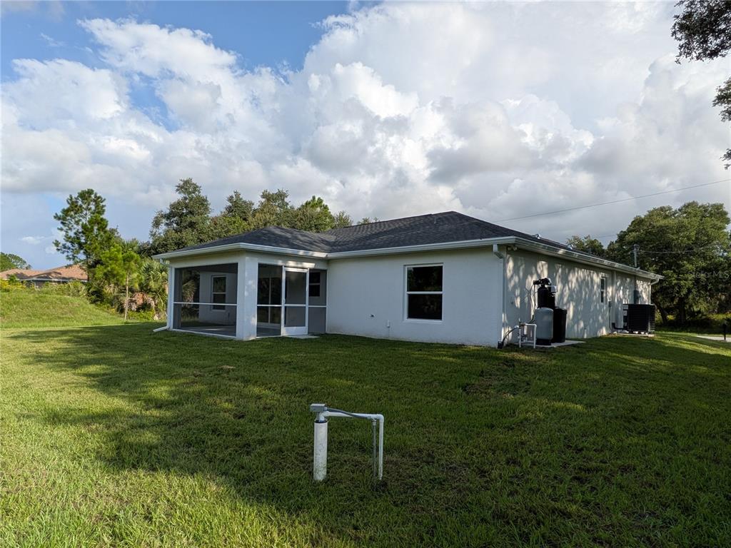 The exterior of a white house features a screened-in porch and a grassy backyard — 6221 LACHINE AVENUE, NORTH PORT, FL