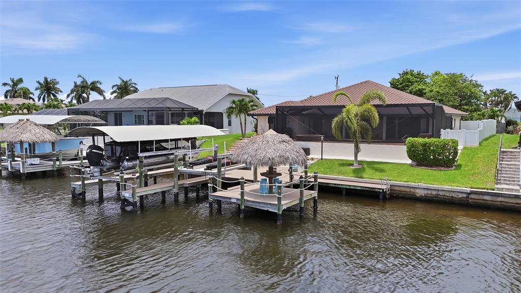 A waterfront house features a boat lift, a tiki hut, and a screened-in patio — 3221 SE 10TH AVENUE, CAPE CORAL, FL