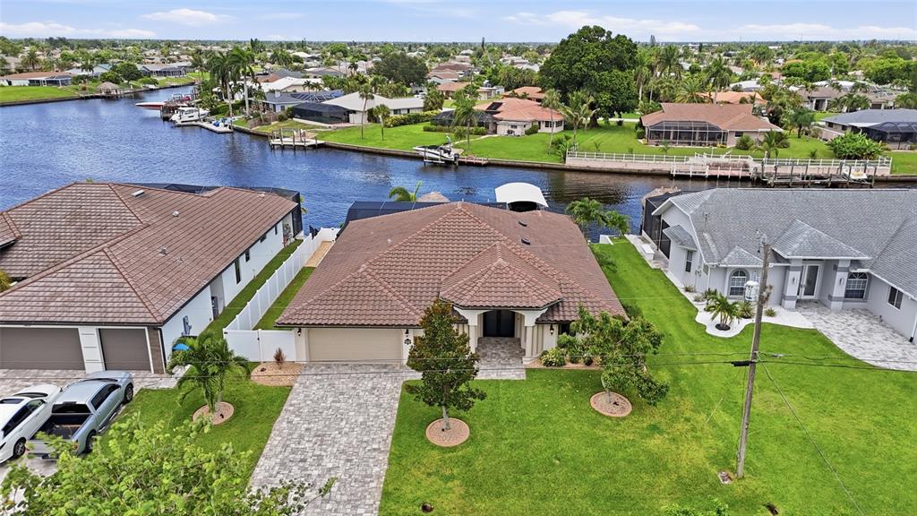 An aerial view shows a suburban house with a tiled roof, driveway, and backyard canal — 3221 SE 10TH AVENUE, CAPE CORAL, FL