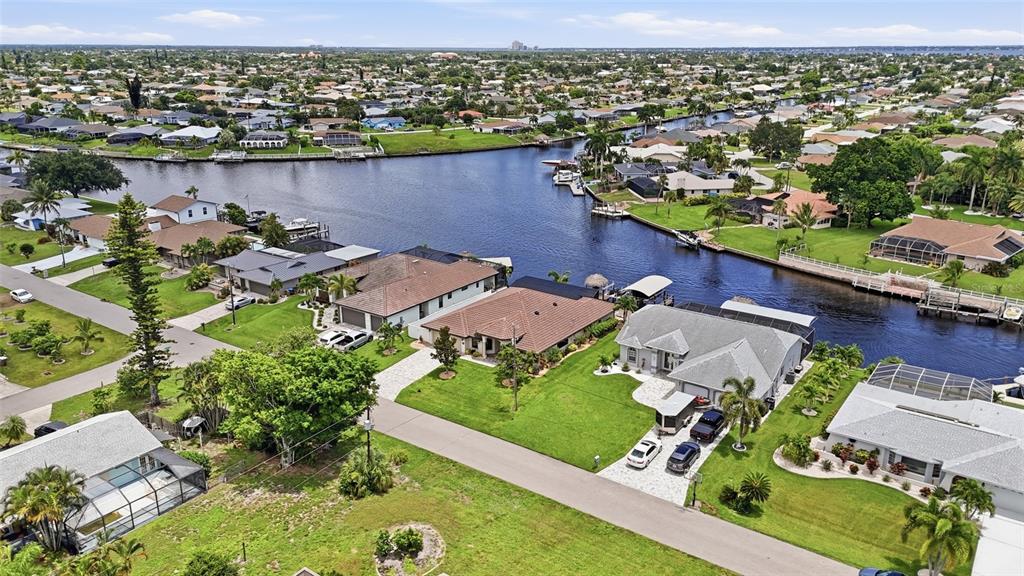An aerial view shows waterfront houses with pools and docks along a canal in Florida — 3221 SE 10TH AVENUE, CAPE CORAL, FL