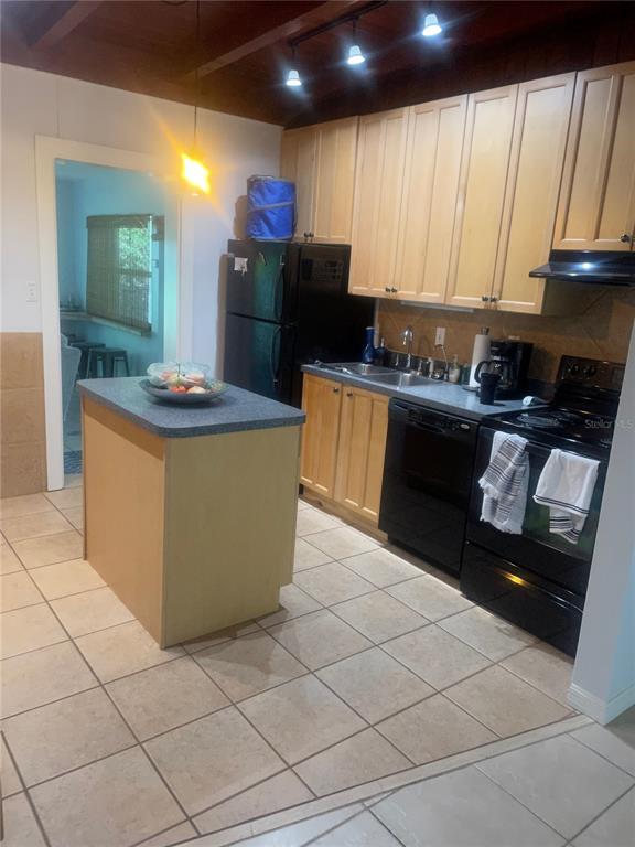 A kitchen features light wood cabinets, black appliances, a central island, and tiled flooring — 428 COURT STREET, ENGLEWOOD, FL