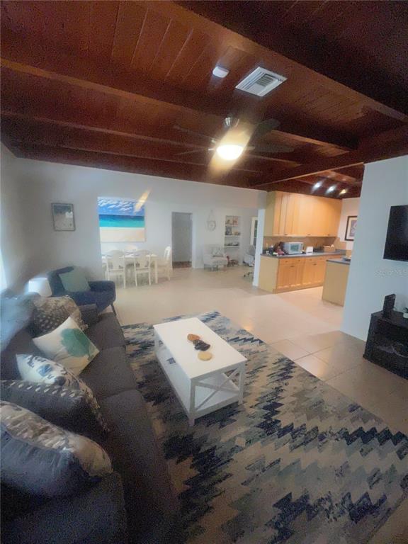 A living room with a wood-beamed ceiling, a patterned rug, and an open-concept kitchen — 428 COURT STREET, ENGLEWOOD, FL