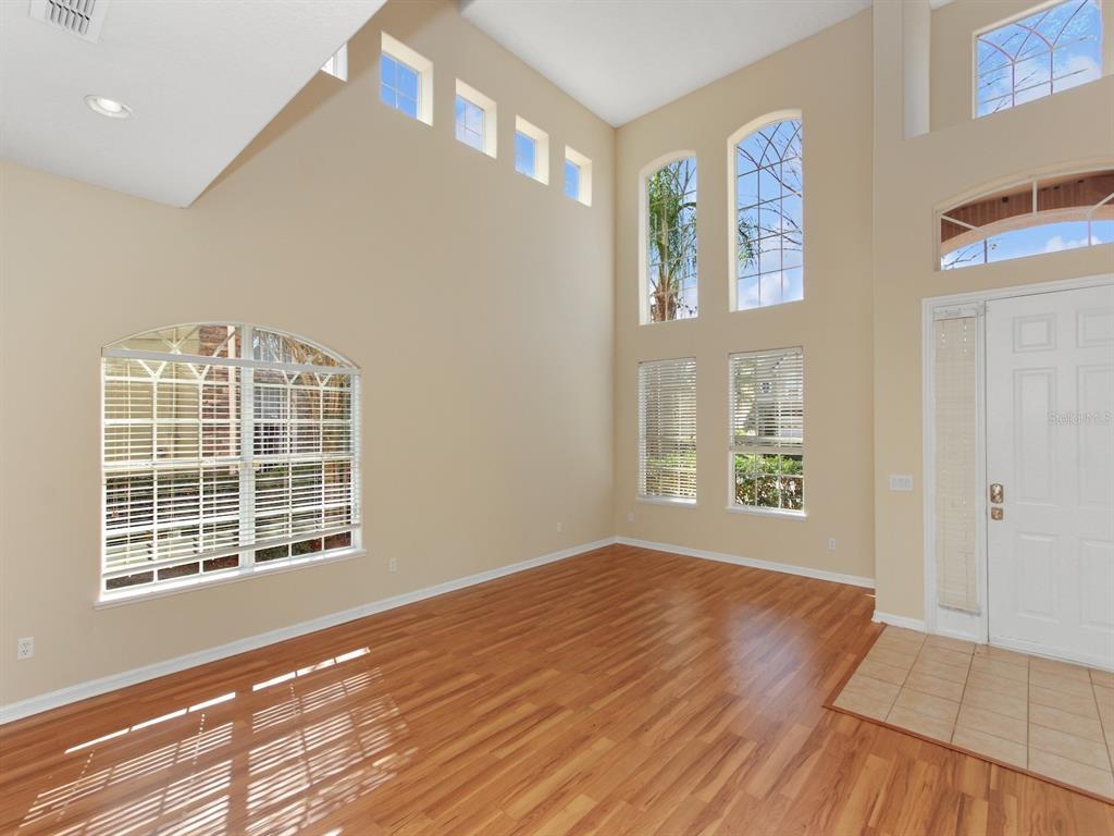 A bright living room features high ceilings, hardwood floors, and multiple large windows — 408 RIVER SONG COURT, ORLANDO, FL