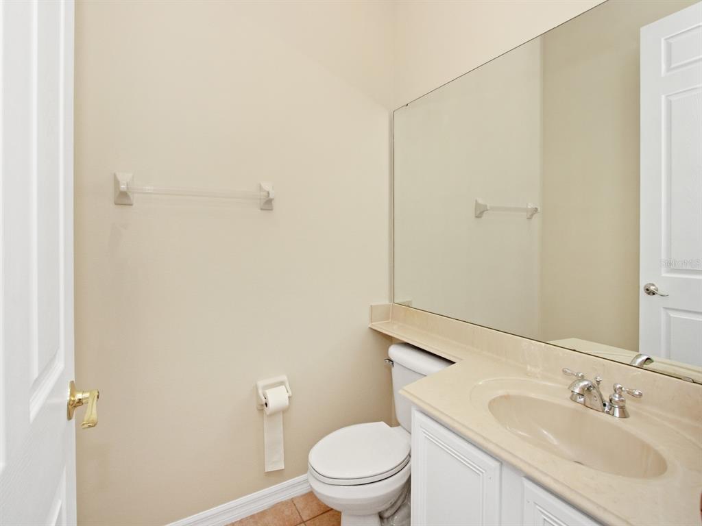 A small bathroom features a white toilet, a vanity with a beige countertop, and mirror — 408 RIVER SONG COURT, ORLANDO, FL