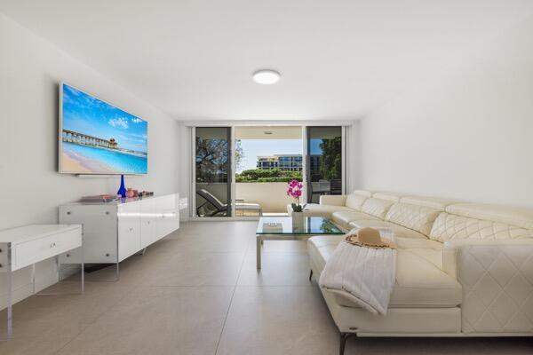 A bright living room features a white sectional sofa, a media console, and sliding glass doors — 2773 S Ocean Boulevard # 214, Palm Beach FL 33480, PALM BEACH, FL