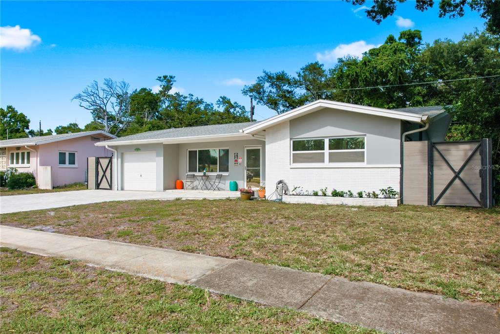 A single-story house with a white brick facade, gray trim, and a concrete driveway — 1144 WOODBROOK DRIVE, LARGO, FL