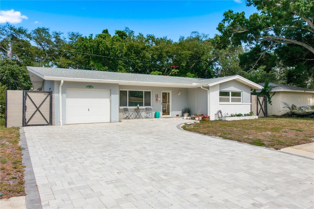 A single-story house with a gray exterior, white garage door, and a paved driveway — 1144 WOODBROOK DRIVE, LARGO, FL