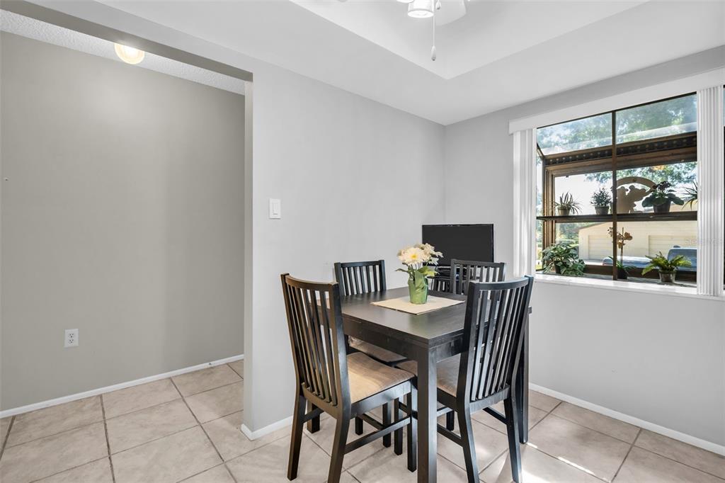 A dining area with a dark wood table, four chairs, and a window overlooking outdoors — 860 MACLAREN DRIVE N UNIT B, PALM HARBOR, FL