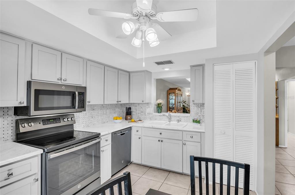 A kitchen features gray cabinets, stainless steel appliances, white countertops, and a ceiling fan — 860 MACLAREN DRIVE N UNIT B, PALM HARBOR, FL