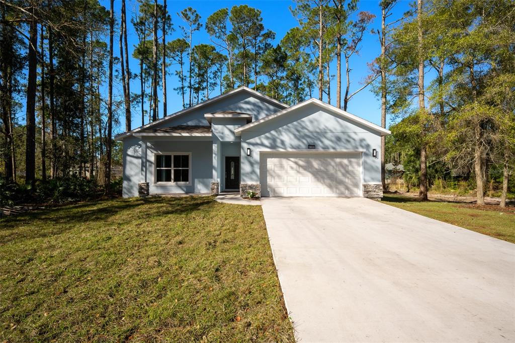 A light blue single-story house with a two-car garage and a concrete driveway — 2390 9TH AVE, DELAND, FL