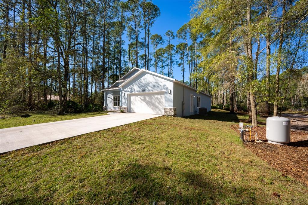 A light blue house with a two-car garage sits on a grassy lot with trees — 2390 9TH AVE, DELAND, FL