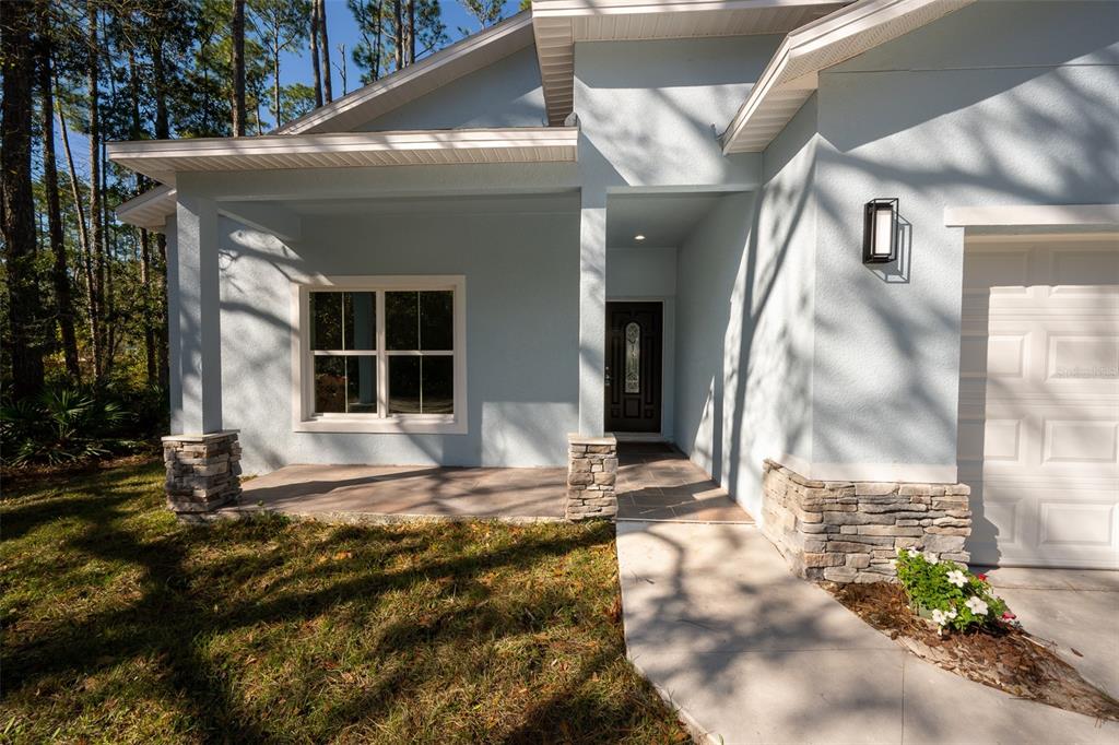 A light blue house exterior features a covered porch, stone pillars, and a front entrance — 2390 9TH AVE, DELAND, FL