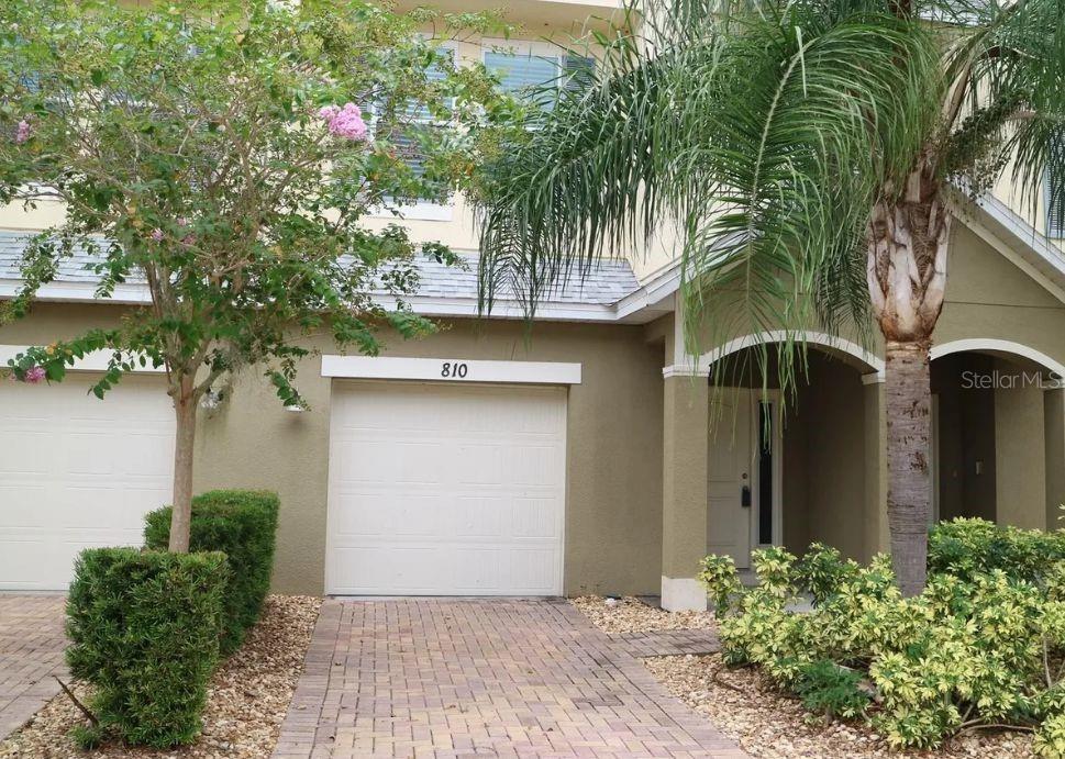 The exterior of a two-story townhouse features a garage, a front entrance, and landscaping — 810 CALLISTA CAY LOOP, TARPON SPRINGS, FL