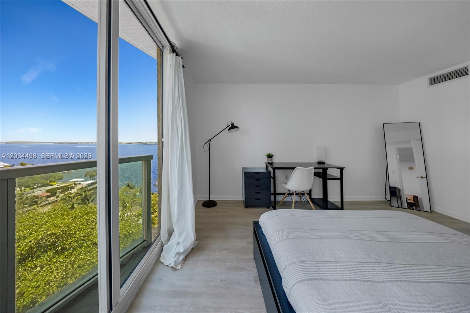 A bedroom features a desk, a bed, and a balcony with a water view — 2101 Brickell Ave # 605, Miami FL 33129, MIAMI, FL