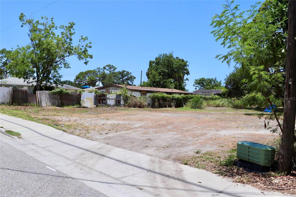 A vacant, flat residential lot with a sidewalk in the foreground and neighboring houses behind — 0 MANGO AVENUE, SARASOTA, FL