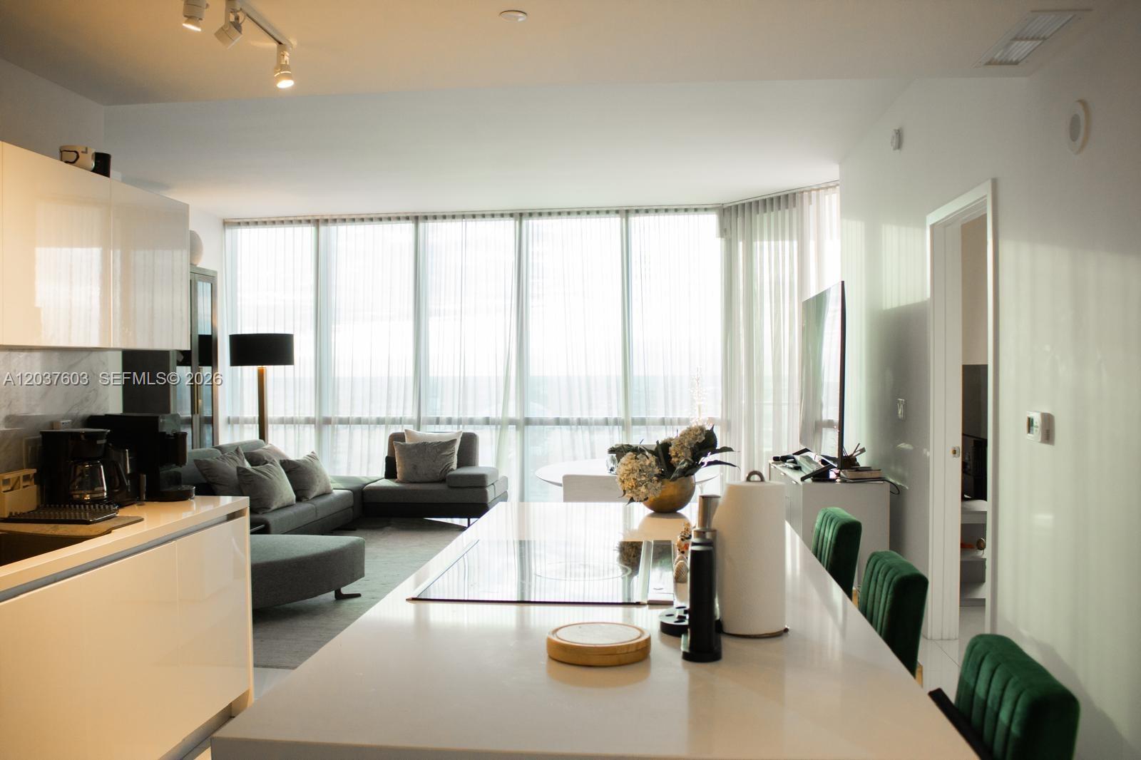 A modern open-concept kitchen and living area features white cabinetry, a large island, and floor-to-ceiling windows — 851 NE 1st Ave # 4806, Miami FL 33132, MIAMI, FL