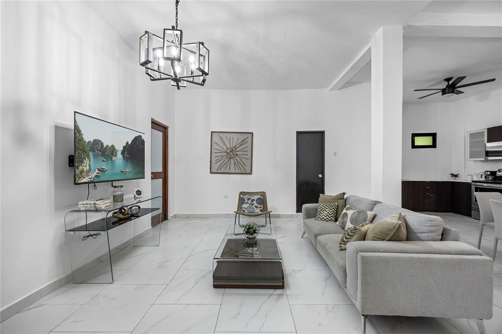 A living room features white tiled floors, a grey sofa, and a modern chandelier — 152 LUNA, SAN JUAN, PR